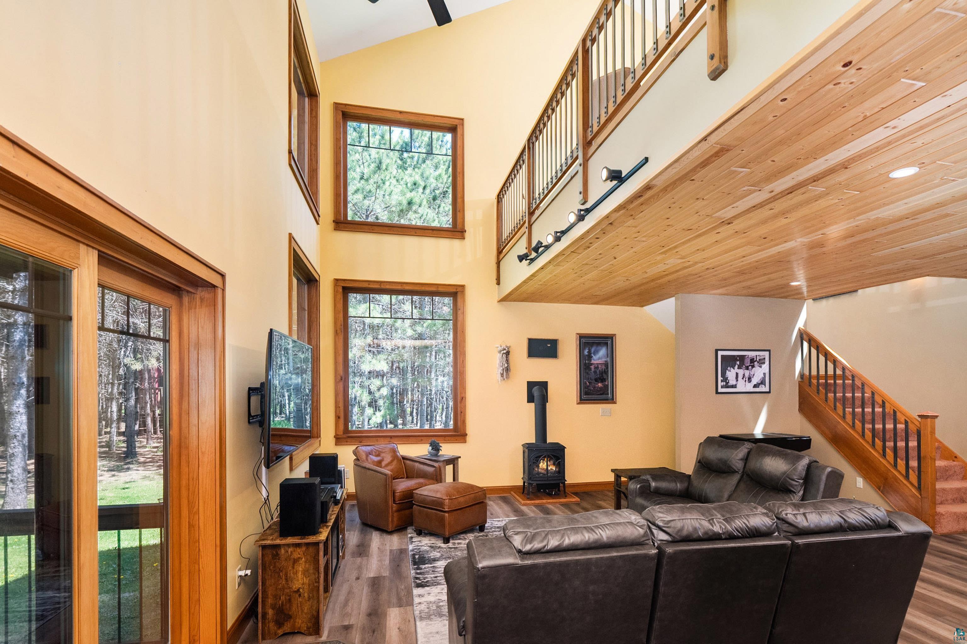 75 East Stark Road Esko, MN 55733 - Photo 15 of 87 Spacious living area featuring a two-story ceiling, a wood-burning stove, and multiple large windows with wood trim