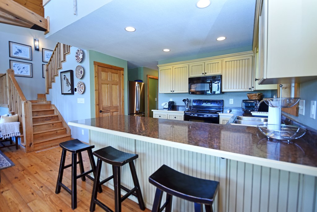 299 Bethabara View Hayesville, NC 28904 - Photo 41 of 131 a kitchen with stainless steel appliances granite countertop a stove top oven a refrigerator a sink and a dining table with white cabinets
