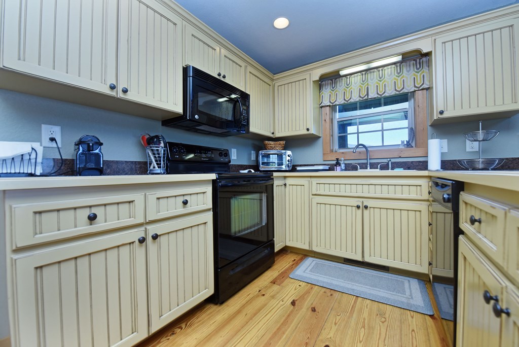 299 Bethabara View Hayesville, NC 28904 - Photo 42 of 131 a kitchen with stainless steel appliances granite countertop a sink dishwasher stove and white cabinets with wooden floor