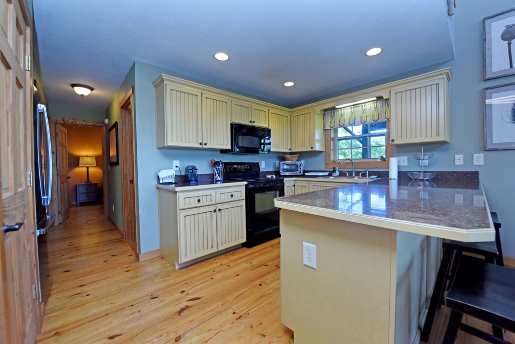 299 Bethabara View Hayesville, NC 28904 - Photo 44 of 131 a kitchen with kitchen island granite countertop a sink cabinets and wooden floor