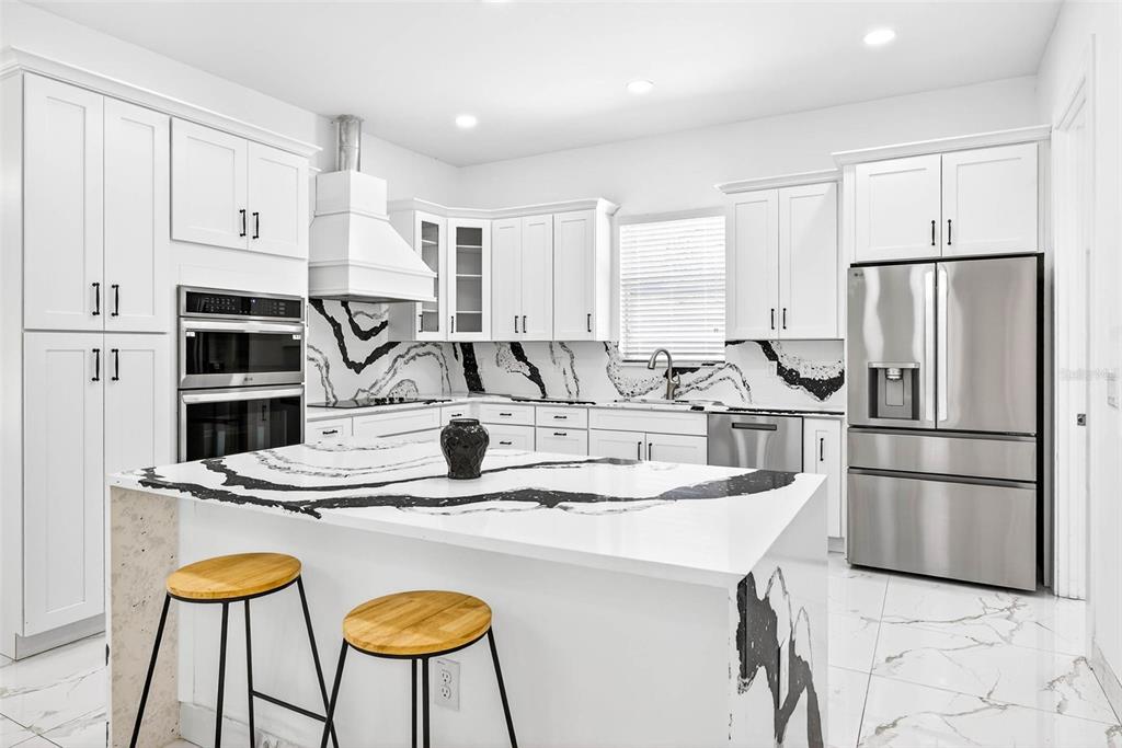 216 North Glen Arven Avenue Temple Terrace, FL 33617 - Photo 30 of 61 a kitchen with stainless steel appliances granite countertop a sink a stove a refrigerator and white cabinets with wooden floor