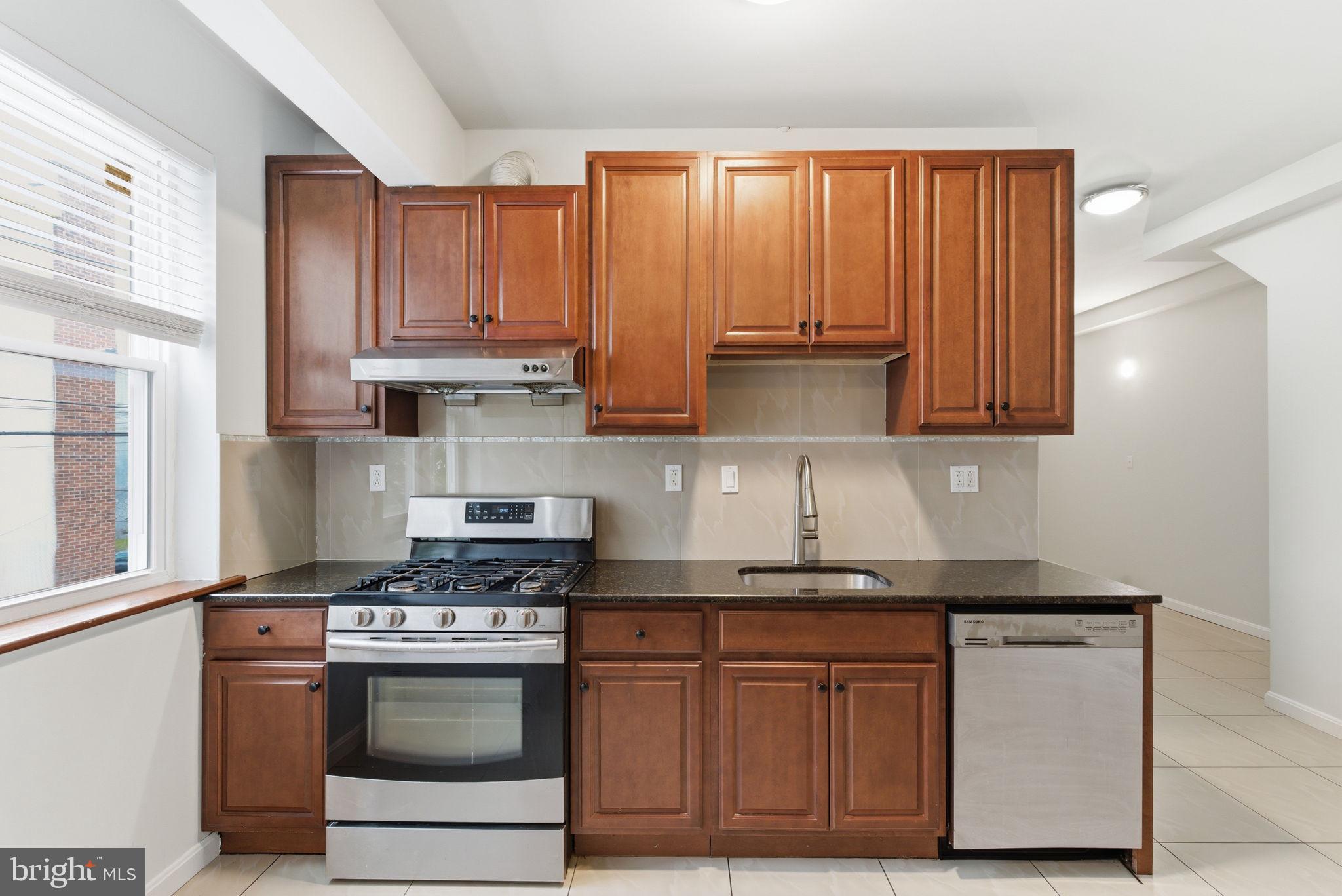 1926 South 7th Street, Unit 2 Philadelphia, PA 19148 - Photo 7 of 18 a kitchen with stainless steel appliances granite countertop a stove a sink and a refrigerator