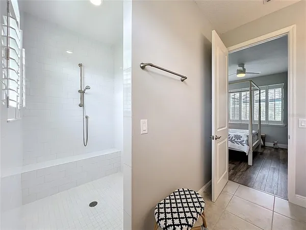 a walk in closet and view of bathroom with tub