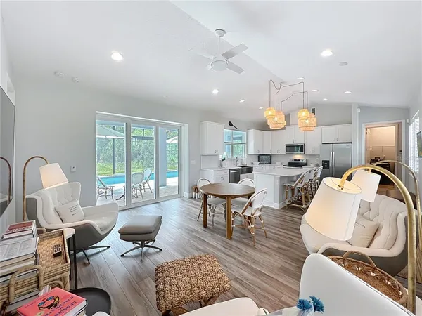 a living room with furniture kitchen view and a large window