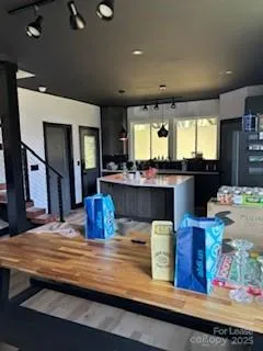 a kitchen with stainless steel appliances granite countertop a sink dishwasher a stove and a dining table with wooden floor