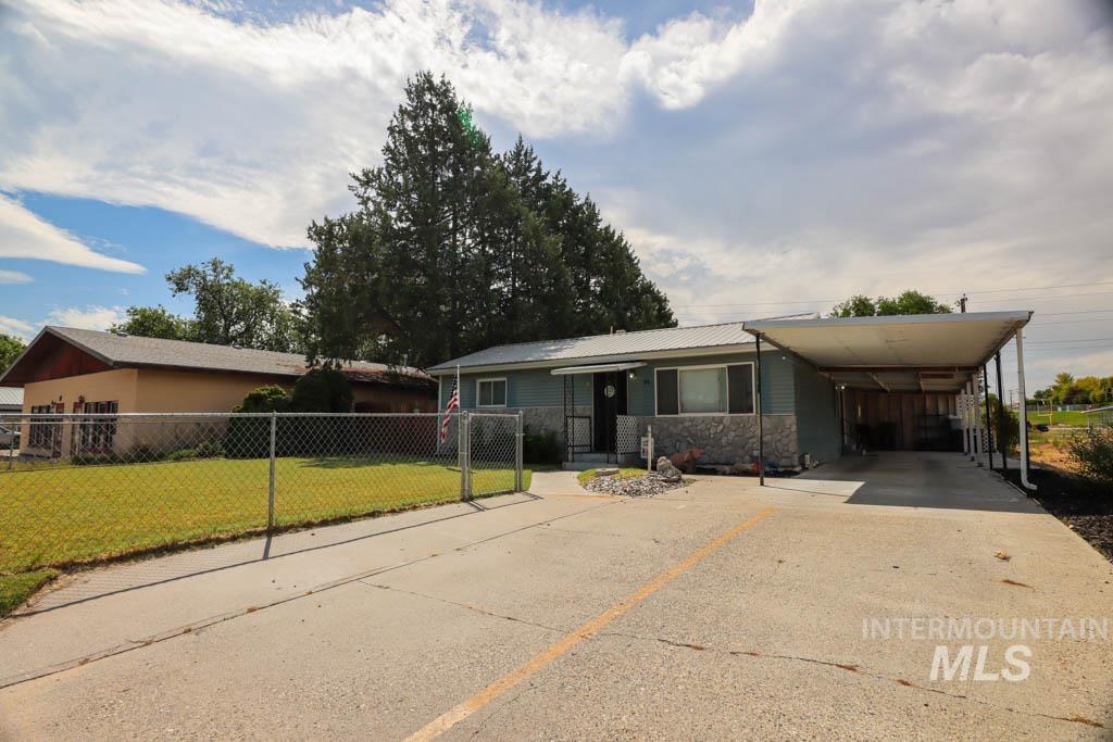 View of front of property featuring driveway, a carport, stone siding, and a metal roof