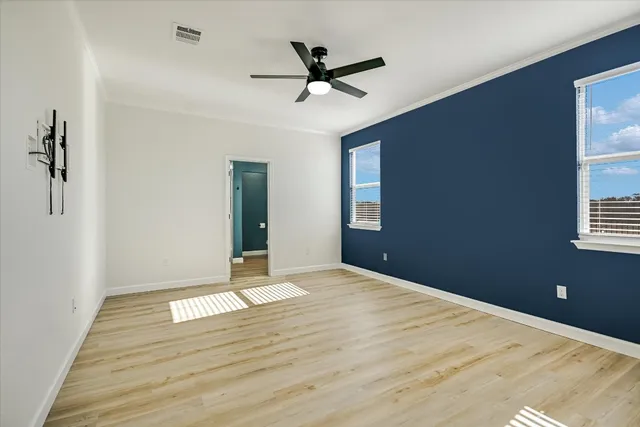 a view of empty room with wooden floor and ceiling fan