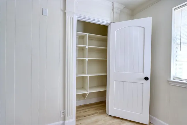 a view of an empty room with a window and wooden floor