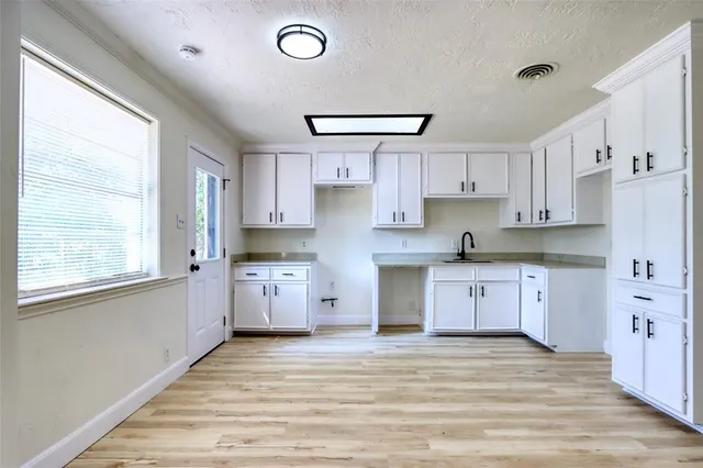 a kitchen with granite countertop a refrigerator and white cabinets