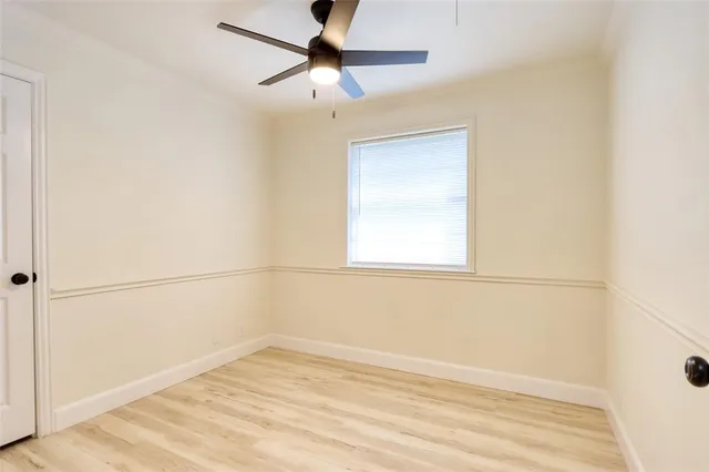 an empty room with a window and a ceiling fan