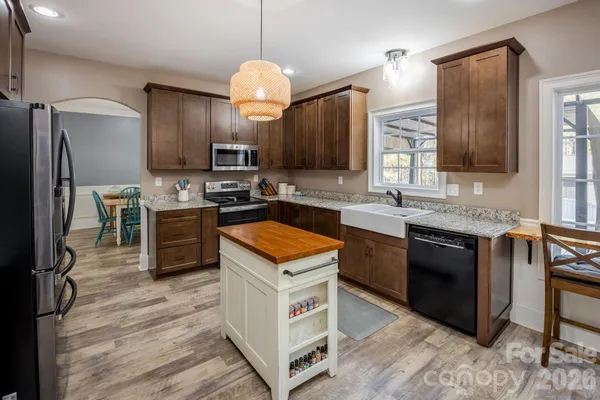 a kitchen with stainless steel appliances granite countertop a stove top oven a sink dishwasher a refrigerator and a oven with wooden floor