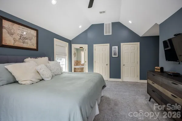a bedroom with a large bed and a flat tv screen on dresser