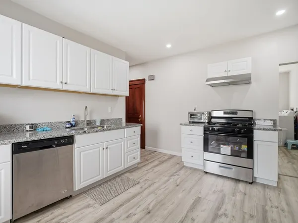 a kitchen with granite countertop a sink cabinets and stainless steel appliances