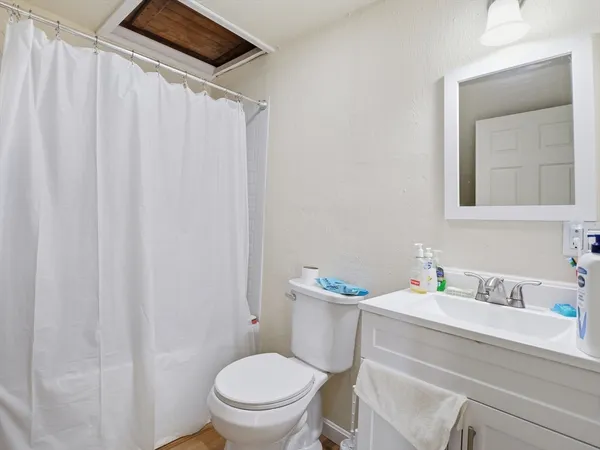 a bathroom with a toilet a sink and wooden floor