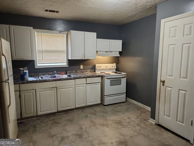 a kitchen with cabinets appliances a sink and a window
