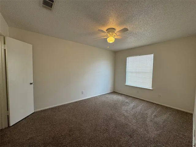 an empty room with a window and a ceiling fan