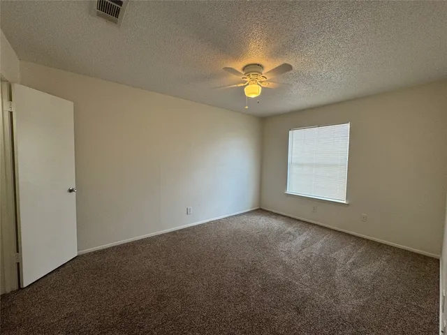 an empty room with a window and a ceiling fan