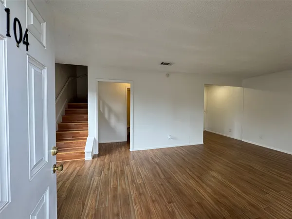 a view of a hallway with wooden floor and stairs