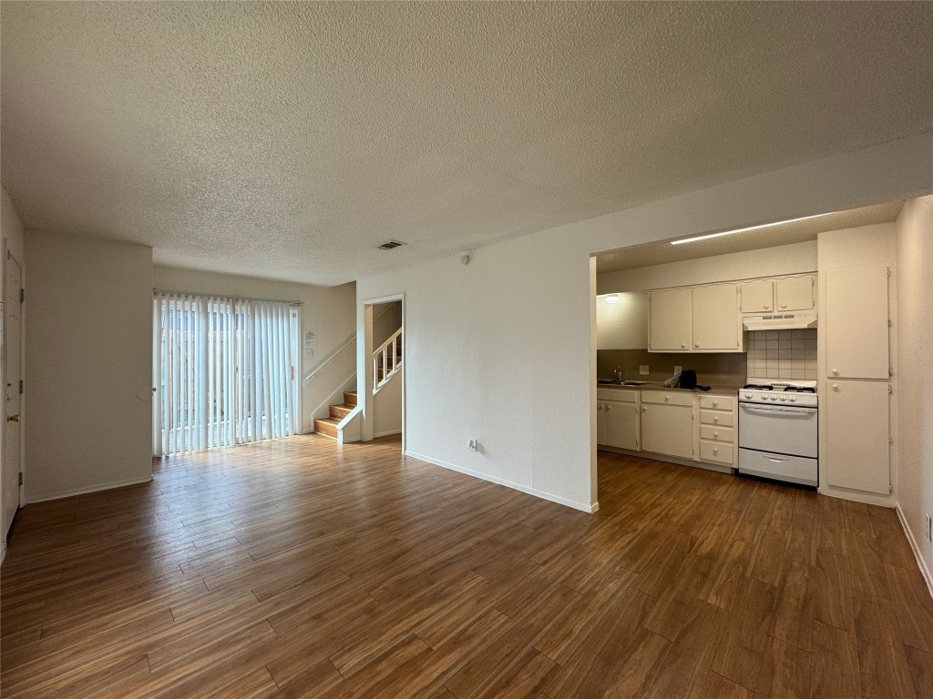 4810 West Wind Trail, Unit 104 Austin, TX 78745 - Photo 3 of 21 a view of a kitchen and an empty room with wooden floor
