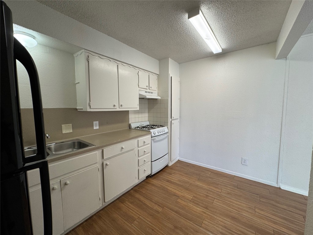 4810 West Wind Trail, Unit 104 Austin, TX 78745 - Photo 6 of 21 a large white kitchen with sink and cabinets