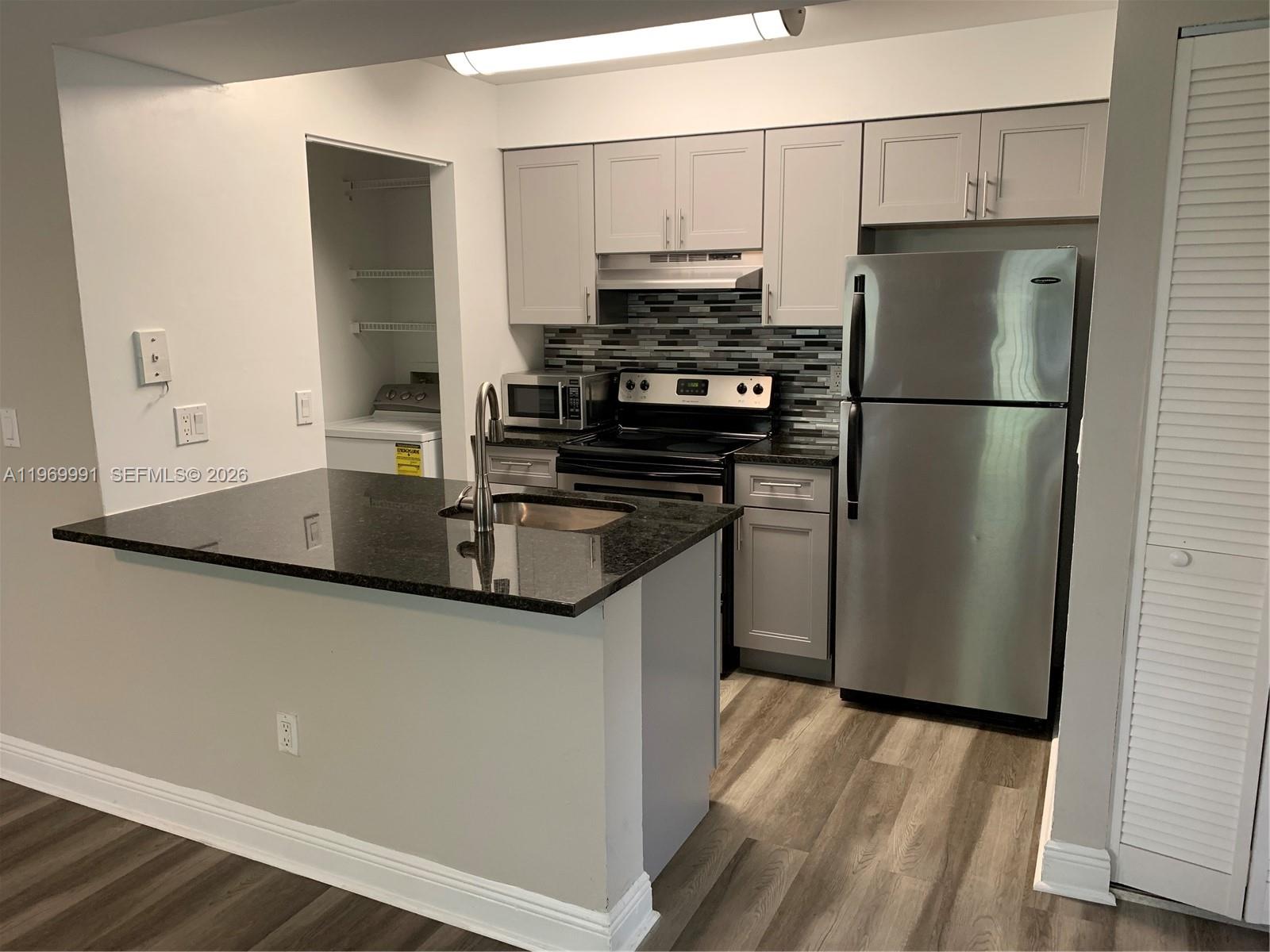 a kitchen with stainless steel appliances granite countertop a refrigerator a stove and a sink