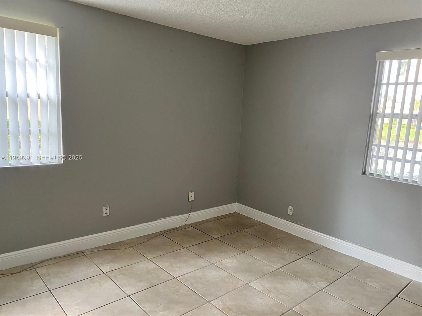 1261 Southwest 46th Avenue, Unit 2003 Pompano Beach, FL 33069 - Photo 5 of 9 an empty room with windows and chandelier fan