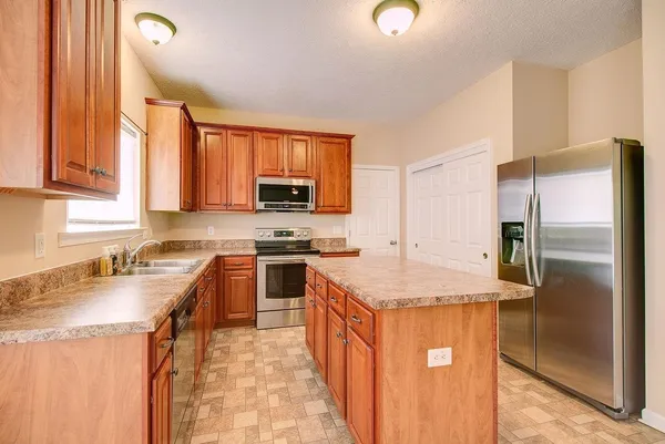 a kitchen with stainless steel appliances granite countertop a sink stove microwave and refrigerator