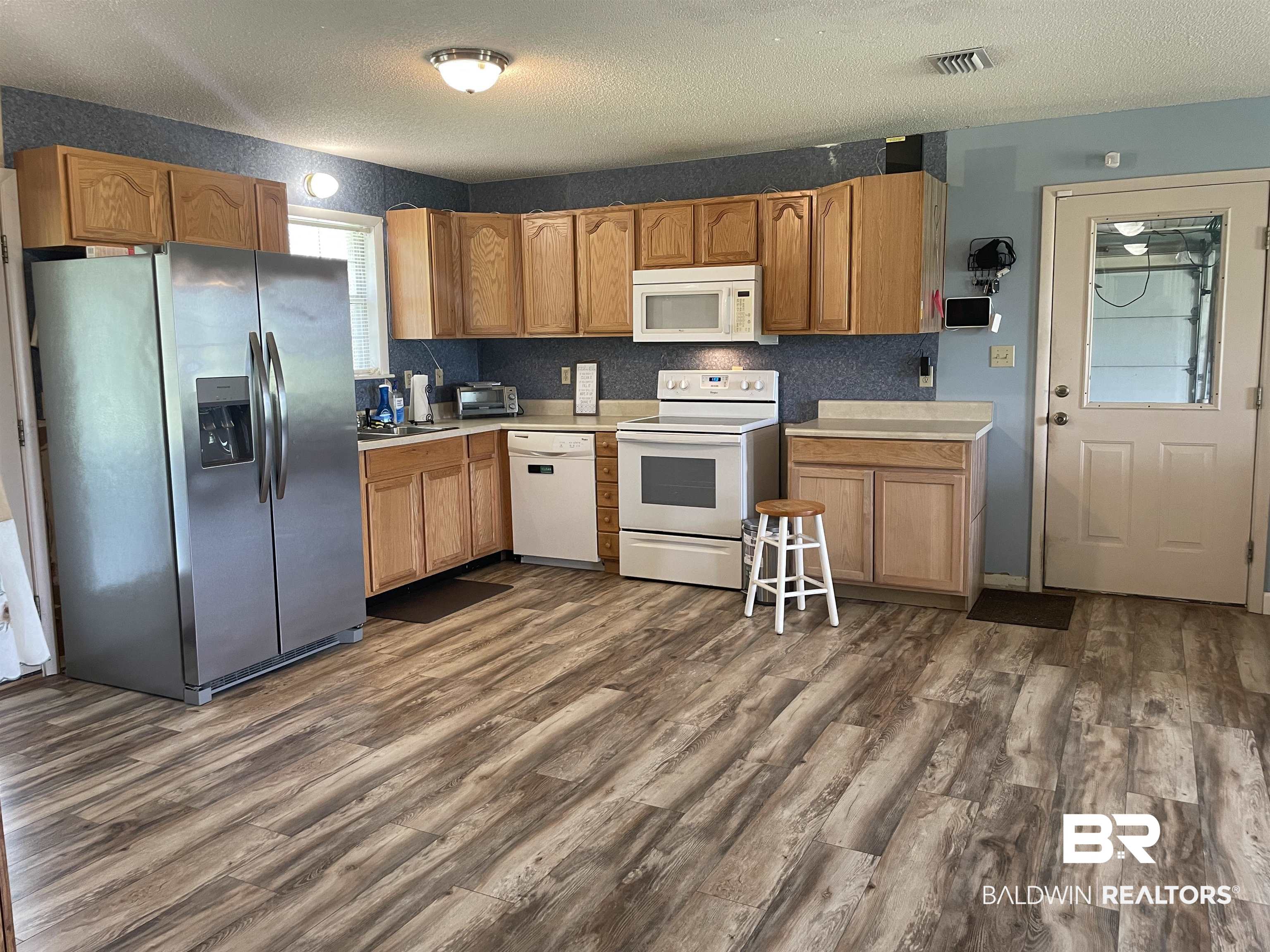 739 Smithfield Road Atmore, AL 36502 - Photo 4 of 18 Kitchen with light countertops, dark wood finished floors, visible vents, and white appliances
