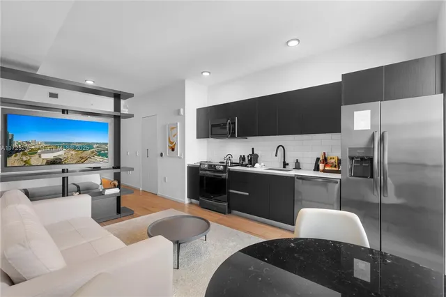 a kitchen with stainless steel appliances granite countertop a sink a stove a refrigerator cabinets and a dining table