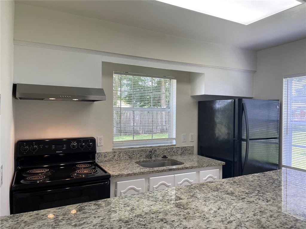 5254 Davisson Avenue, Unit 5254 Orlando, FL 32810 - Photo 6 of 15 a kitchen with granite countertop a refrigerator a stove and a refrigerator