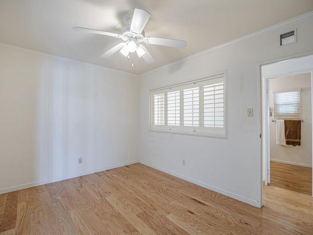 an empty room with wooden floor fan and windows