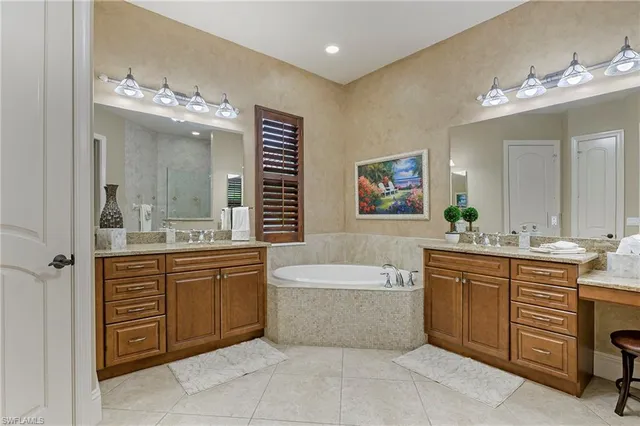 a spacious bathroom with a double vanity sink large mirror and a bathtub