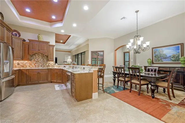 a dining room filled chandelier and kitchen view