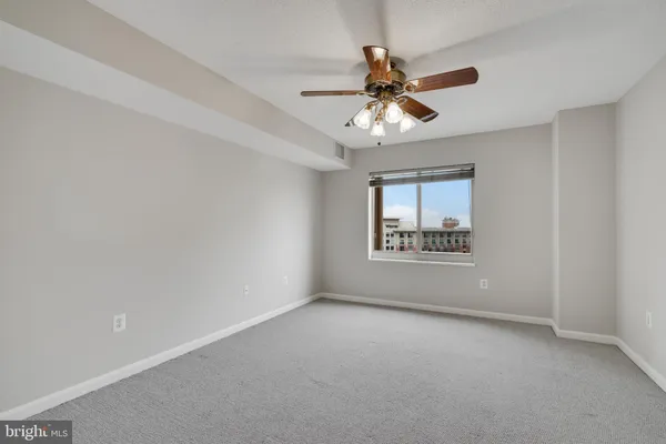 a view of an empty room and chandelier fan