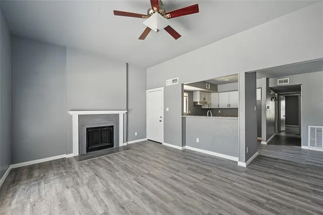 a view of empty room with wooden floor and kitchen view