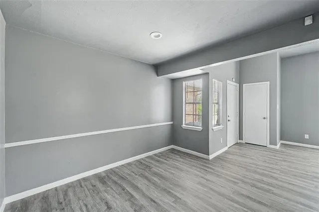 a view of an empty room with window and wooden floor