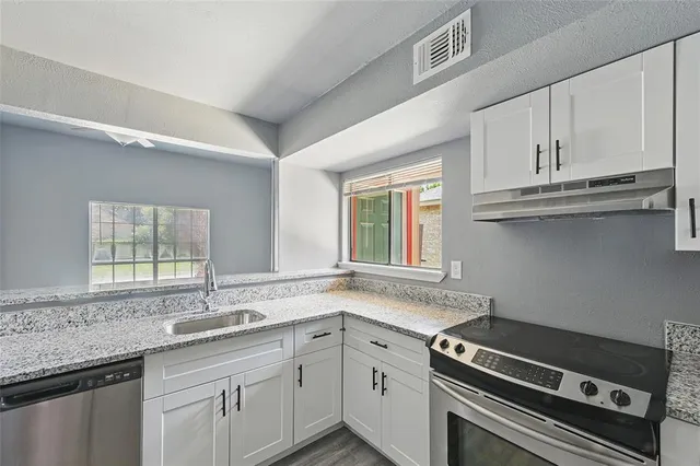 a kitchen with granite countertop a stove sink and cabinets