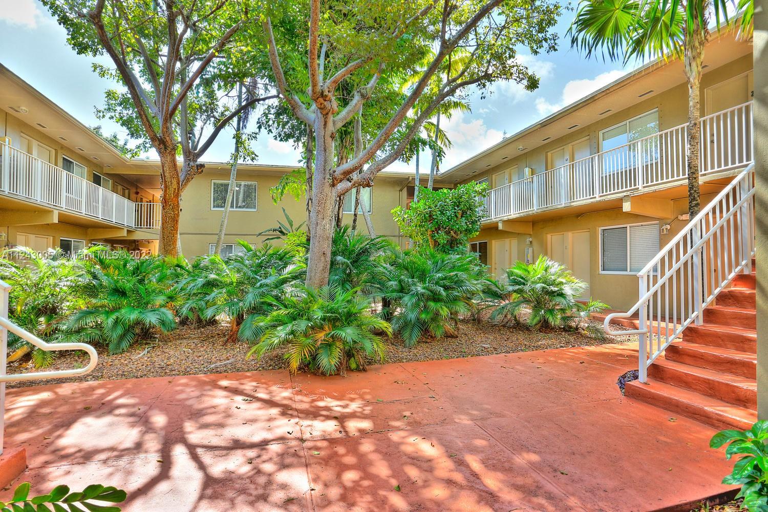 6310 Southwest 79th Street, Unit 18 South Miami, FL 33143 - Photo 14 of 16 a view of a house with large windows and a small yard