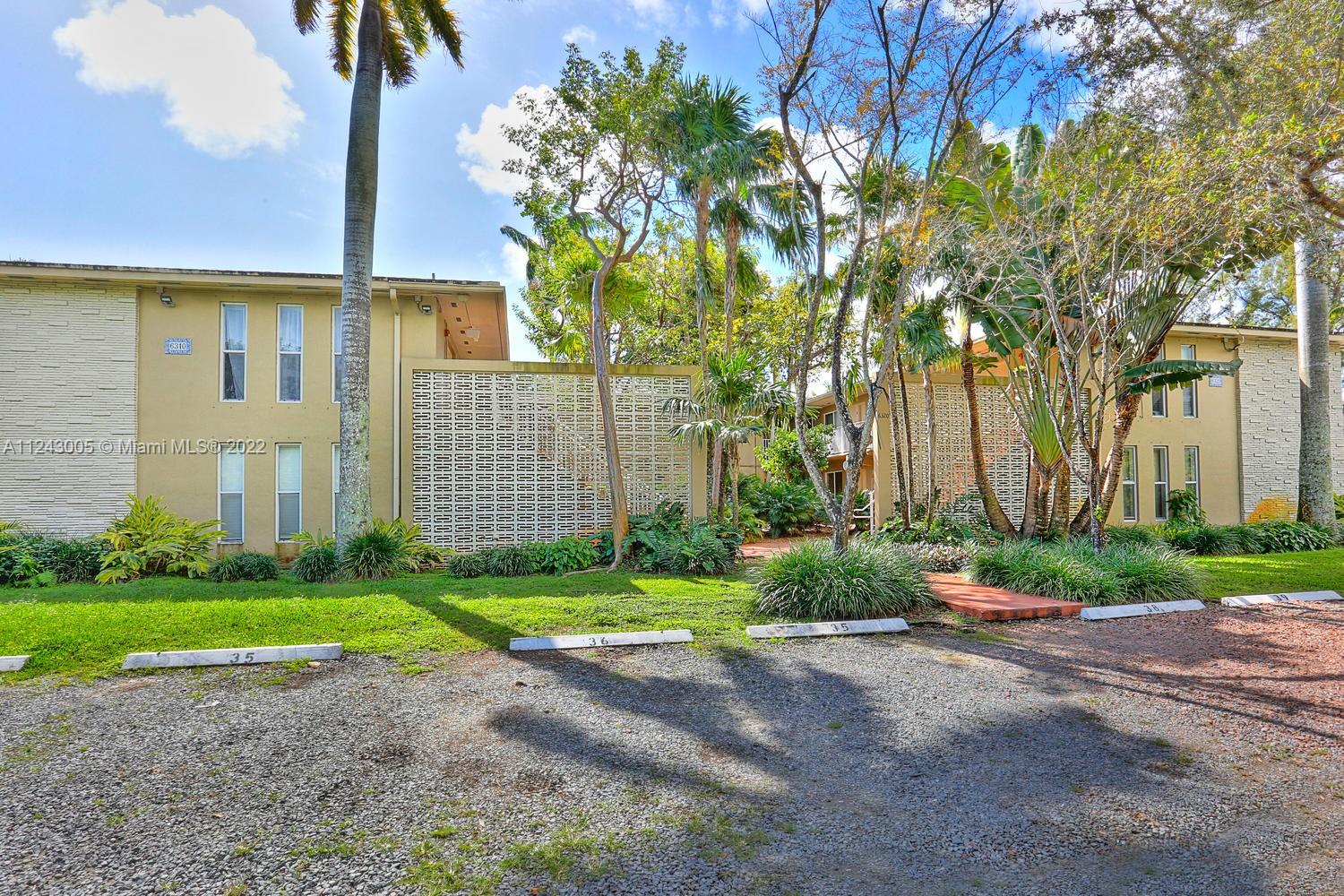 6310 Southwest 79th Street, Unit 18 South Miami, FL 33143 - Photo 15 of 16 a view of a brick house with a yard and large trees