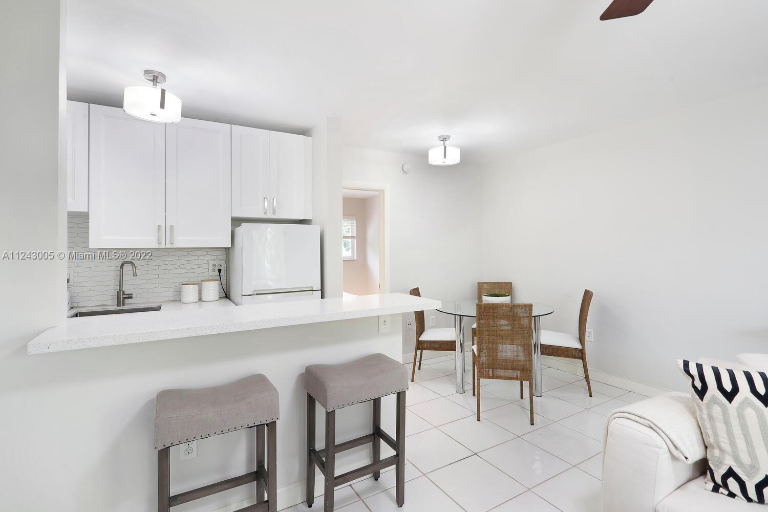 6310 Southwest 79th Street, Unit 18 South Miami, FL 33143 - Photo 7 of 16 a kitchen with a dining table chairs and white cabinets