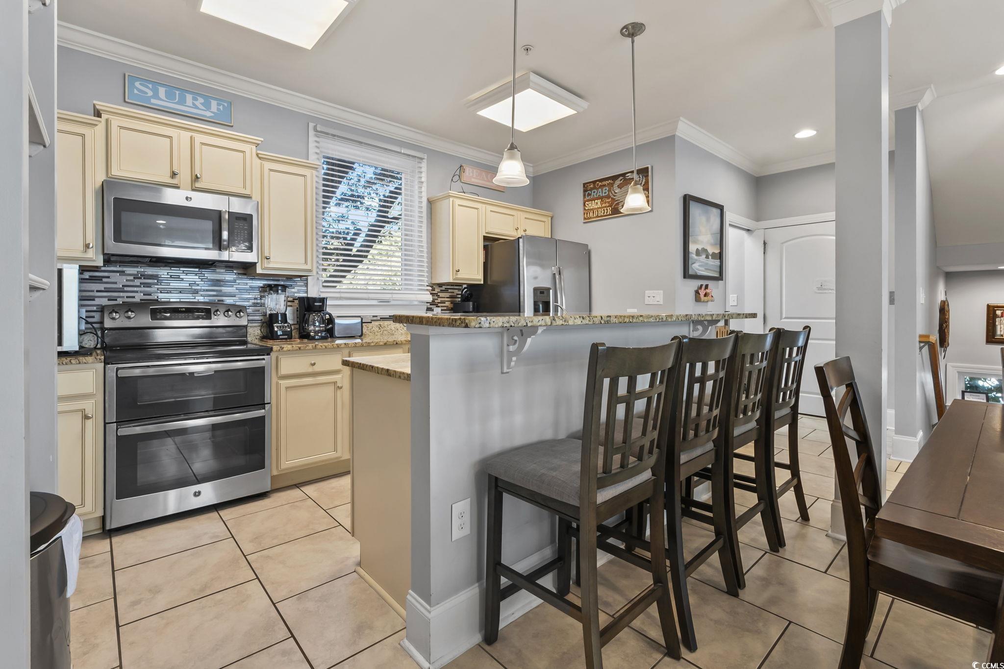 7401 North Ocean Boulevard, Unit 5 Myrtle Beach, SC 29572 - Photo 5 of 34 Kitchen with cream cabinets, appliances with stainless steel finishes, pendant lighting, crown molding, and light stone counters