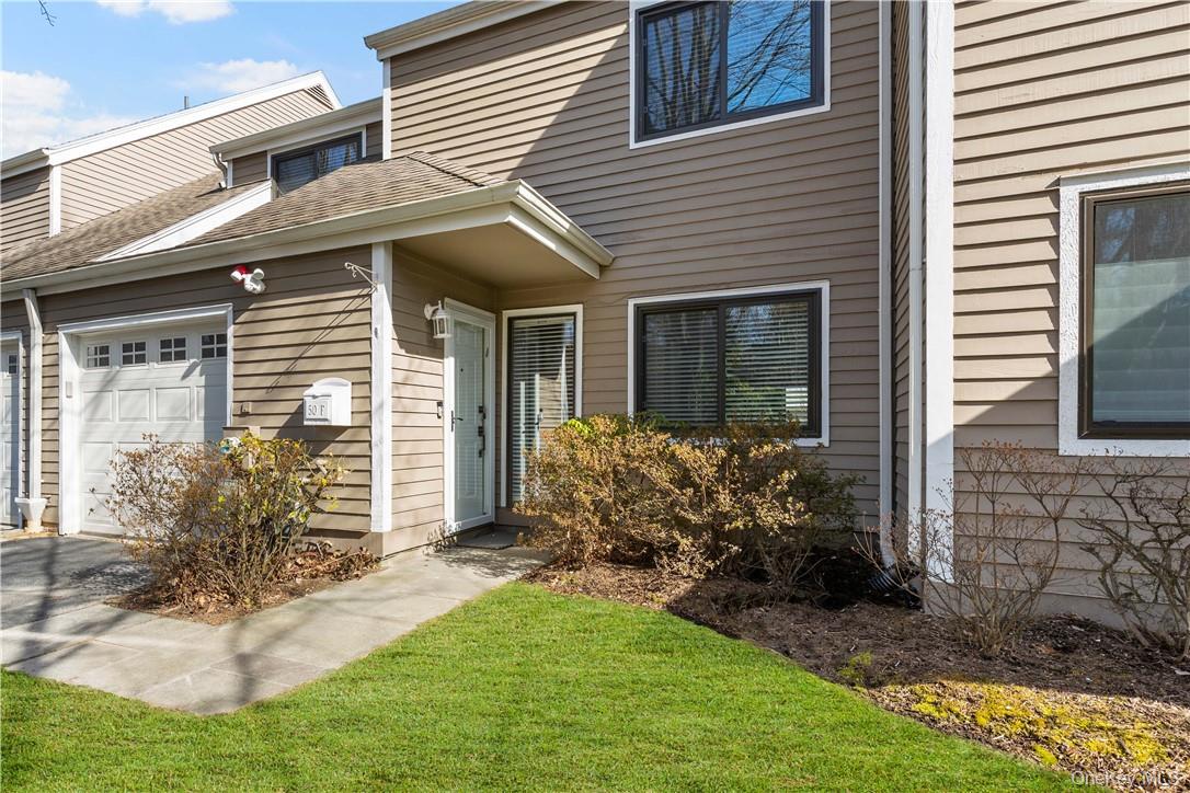 a view of a house with brick walls and a yard with plants