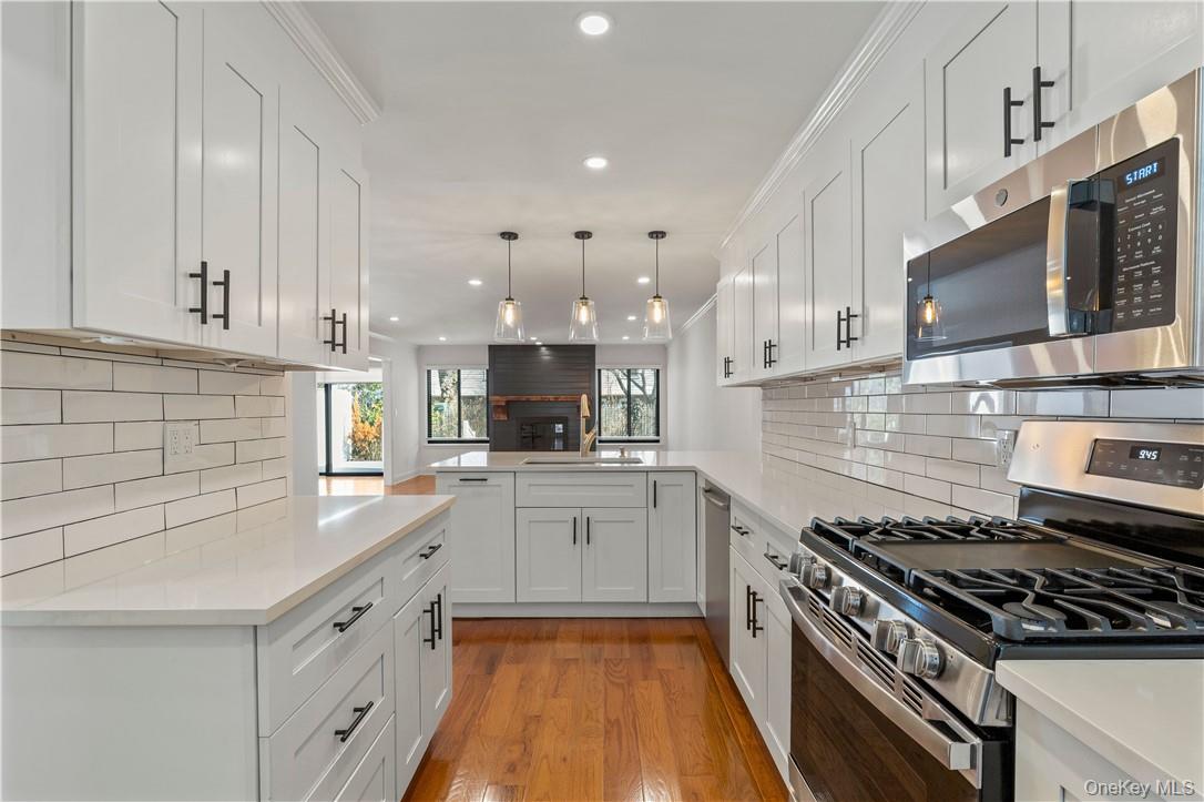 50 Pondview Road, Unit F Rye, NY 10580 - Photo 3 of 25 a kitchen with granite countertop a sink dishwasher stove and white cabinets with wooden floor