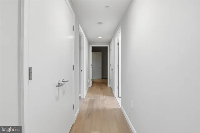 a view of a hallway with wooden floor and a bathroom