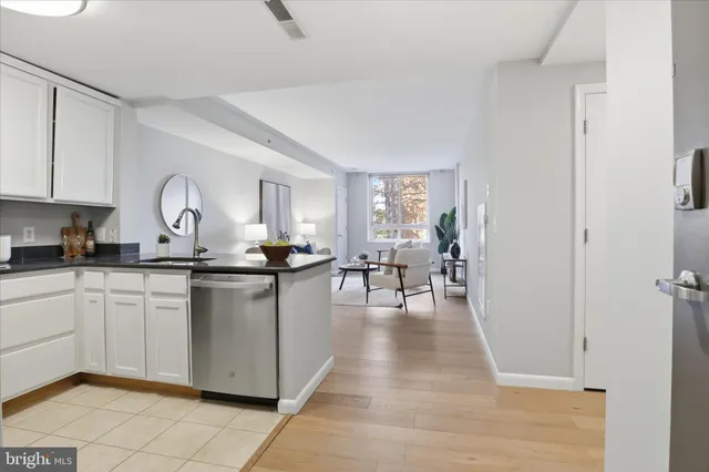 a open kitchen with granite countertop a stove a sink and white cabinets with wooden floor