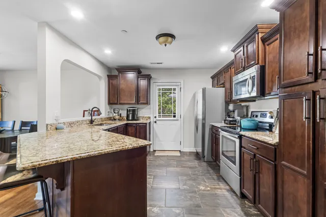 a kitchen with stainless steel appliances granite countertop sink refrigerator and cabinets
