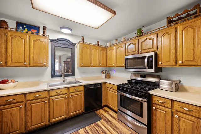 a kitchen with stainless steel appliances granite countertop a stove a sink dishwasher and a microwave oven with wooden cabinets