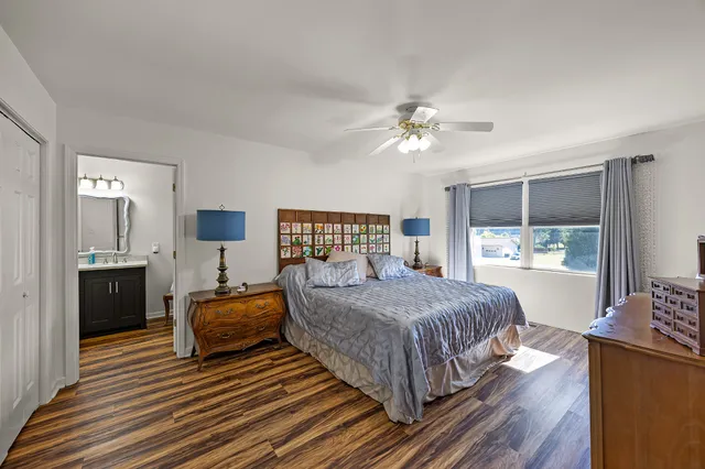 a bedroom with a large bed a chandelier with dresser and mirror
