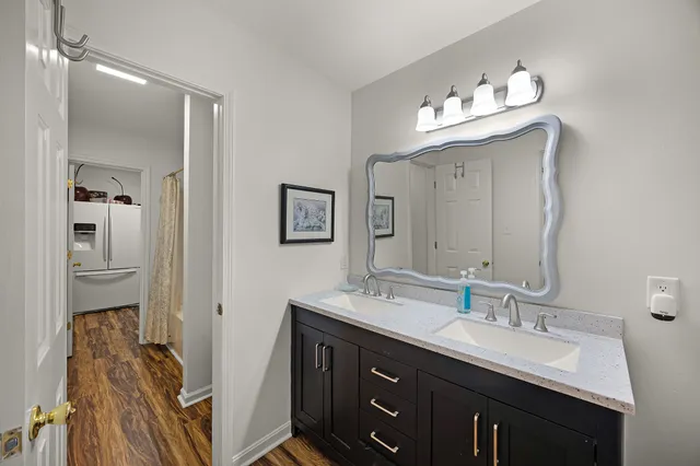 a bathroom with double vanity sinks a vanity a lamp and a mirror