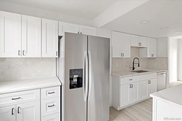 a kitchen with white cabinets and refrigerator